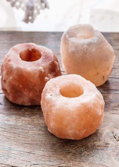 three doughnuts sitting on top of a wooden table next to a glass vase