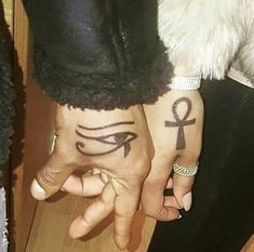 two people with tattoos on their hands holding each other's hand and one has an eye