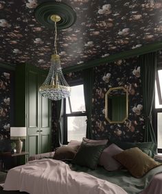 a bedroom with floral wallpaper, green walls and a chandelier hanging from the ceiling