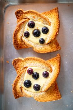 two pieces of bread with blueberries and cream cheese on them sitting in a pan