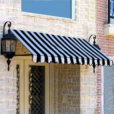 a black and white awning on the side of a brick building next to a lamp post