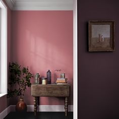 a room painted in pink and purple with a small wooden table next to the door