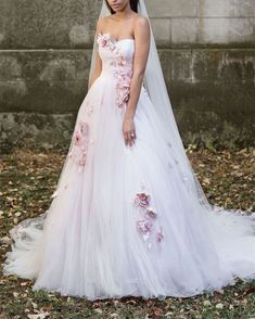 a woman wearing a wedding dress with flowers on the side and veil over her head