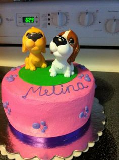 there is a pink cake with two dogs on it