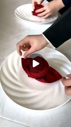 two people are decorating plates with red cloths on them and one person is holding a piece of fabric