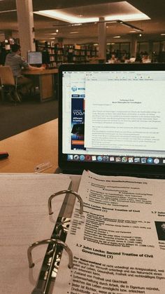 an open laptop computer sitting on top of a table next to a book and glasses