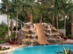 a water slide in the middle of a pool surrounded by palm trees