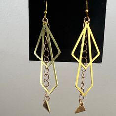 Gorgeous, fun earring - perfect for a party! Brass triangles dangle from chains framed by brass double diamonds. Gold hooks. Gold Geometric Jewelry For Party, Diamond-shaped Gold Jewelry For Party, Gold Diamond-shaped Party Jewelry, Party Earrings With Adjustable Chain In Brass, Party Brass Earrings With Adjustable Chain, Brass Earrings With Adjustable Chain For Party, Gold Triangle Jewelry With Ear Wire, Triangle Gold Metal Earrings, Gold Triangle Metal Earrings