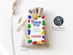 a small bag with a thank you tag on it next to some dried grass and a sticker that says, thank you lucas