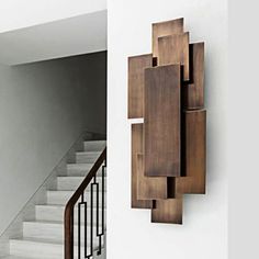 a wall mounted sculpture on the side of a white wall next to a stair case