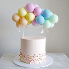 a white cake topped with balloons on top of a table