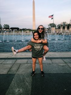 two girls are hugging in front of the washington monument