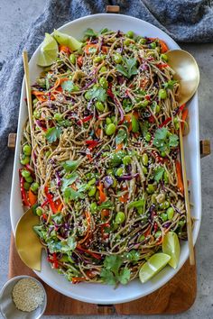 a white plate topped with noodles and veggies next to a bowl of seasoning