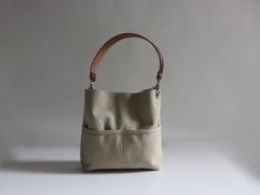 Our soft, sun-washed canvas bucket bag will quickly become your favorite everyday bag. A mid-sized bag in a neutral Sand color with plenty of pockets and the flexibility to choose a shoulder strap, a crossbody strap or both. Versatile, durable and a breeze to carry. To see additional colors and sizes click here: https://www.etsy.com/shop/IndependentReign DETAILS: -Approximately 10.5in H x 11in W x 2.5in D -Durable canvas exterior with a subtle faded finish -2 exterior front pockets -Magnetic sna Everyday Beige Bucket Bag With Pockets, Canvas Bucket Bag With Leather Handles For Everyday Use, Versatile Khaki Canvas Bag For Everyday Use, Everyday Khaki Shoulder Bag With Canvas Lining, Khaki Shoulder Bag With Leather Handles For Everyday, Everyday Khaki Shoulder Bag With Leather Handles, Beige Canvas Hobo Bag For Everyday Use, Khaki Canvas Hobo Bag Tote, Khaki Canvas Shoulder Bag For Everyday Use