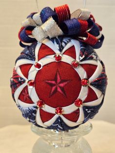 a red white and blue christmas ornament on a clear glass base with beads