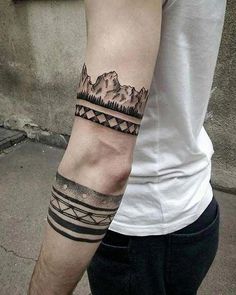 a man with a tattoo on his arm that has mountains and trees in the background