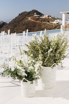 two vases filled with flowers sitting on top of a white floor next to chairs