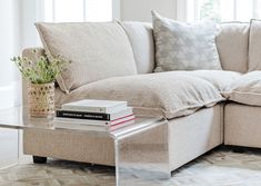 a living room with a couch, coffee table and books on the end tables in front of it