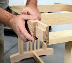 a man is working on a wooden table with two legs and one hand holding the edge