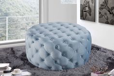 a blue ottoman sitting on top of a shaggy rug in front of a large window