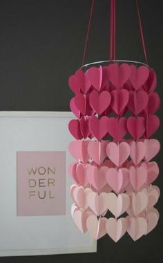 a chandelier made out of paper hearts hanging from it's side with the word wonderful written on it