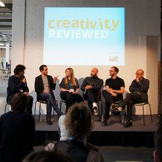 five people sitting on stage talking to each other in front of a large screen with the words creativity reviewed