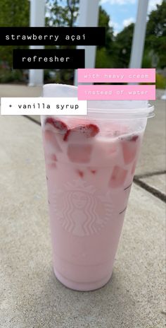 a pink drink with strawberries in it sitting on the ground