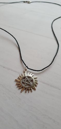 a necklace with a pen and sun on it sitting on top of a wooden table