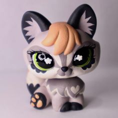 a close up of a small toy cat with big eyes on a white surface background