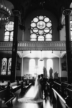 a bride and groom standing in front of stained glass windows at the end of their wedding day