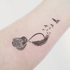 a tattoo on the arm of a woman with birds flying around it and an arrow in the shape of a heart