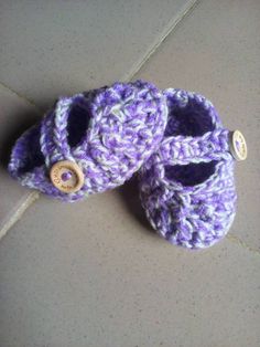 two crocheted baby shoes sitting on top of a tile floor next to each other