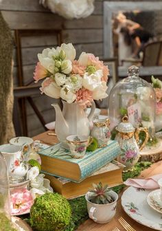 a table topped with books and vases filled with flowers next to an open book