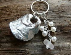 a piece of silver metal with pearls hanging from it's side on a wooden surface