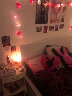 a bedroom with pink and black decorations on the wall, lights strung from the ceiling