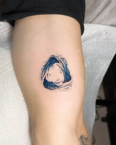 a woman's leg with a tattoo on it that has a blue wave coming out of the water