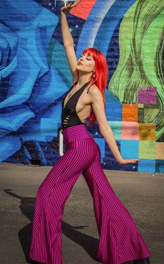 a woman with red hair is dancing in front of a mural