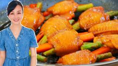 a woman standing in front of a frying pan filled with chicken and veggies