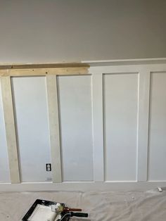 an unfinished room with white paneling and tools on the floor in front of it