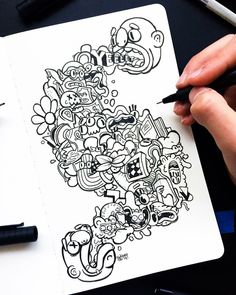 a person holding a pen and drawing on a piece of paper with doodles around it