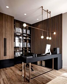 an office with a desk and bookshelf in the corner, surrounded by wooden flooring