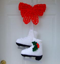 two crocheted ice skates hanging from a door hanger with red bows