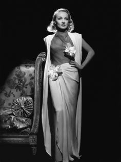 a woman in an evening gown poses for a studio portrait wearing a shawl and flowers