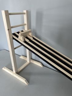 a wooden bench sitting on top of a white floor next to a gray wall with black and white stripes