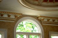 an arched window in the middle of a room with decorative moldings on the ceiling