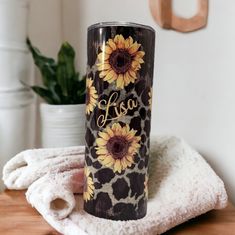 a black and white leopard print tumbler with sunflowers on it sitting on a table