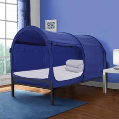 a child's bed in a blue room with white sheets and pillows on the floor