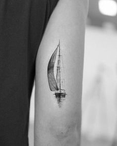 a black and white photo of a sailboat on the back of a man's arm