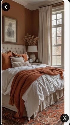 an orange and white bedroom with a large bed in the center, two windows on each side