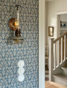 there is a light switch on the wall in this room with blue and white wallpaper